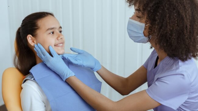 Little kid sit in dental chair at medical center, professional doctor fixing her teeth