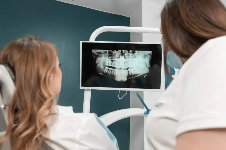 Dentista che guarda una panoramica con il paziente sul lettino